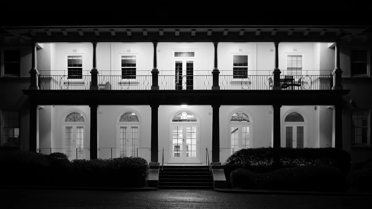 Casarão iluminado à noite em preto e branco, imóvel protegido por alarme monitorado com empresa de plantão