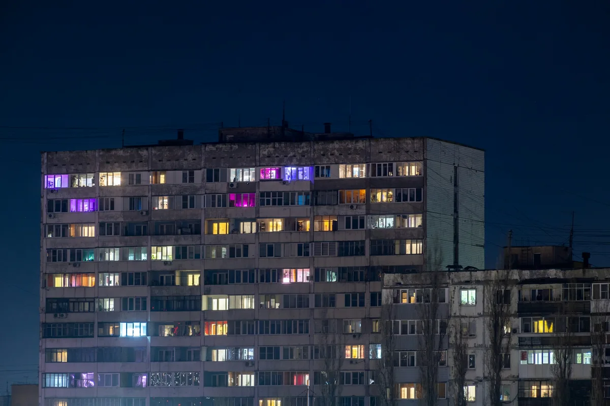 Prédio residencial à noite com janelas acesas, moradias protegidas por alarme monitorado
