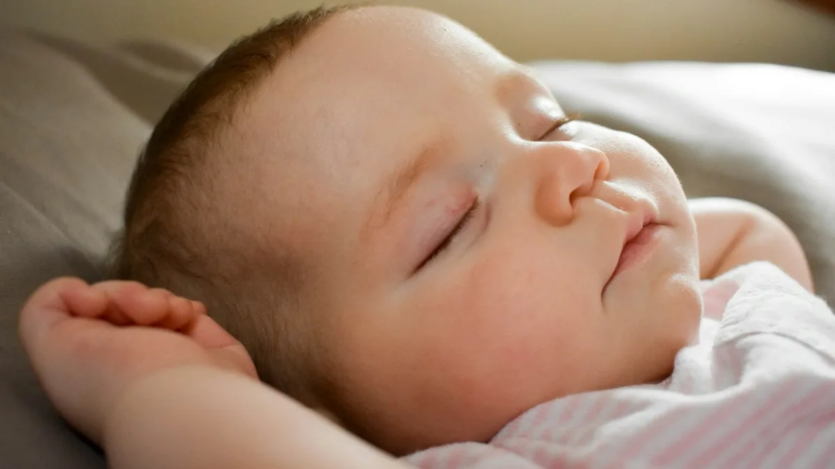 Bebê recém-nascido dormindo de lado, cena que a babá eletrônica acompanha durante a noite