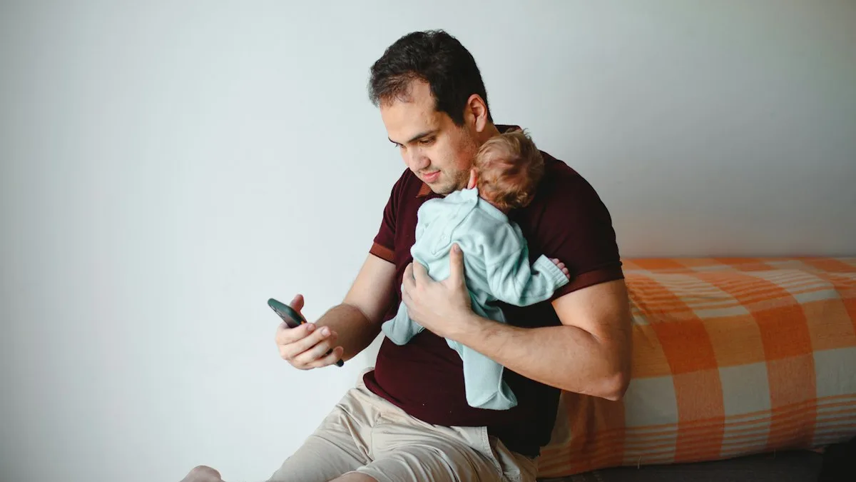Pai sentado no chão com o bebê no colo olhando o celular, ilustrando o uso da babá eletrônica com aplicativo