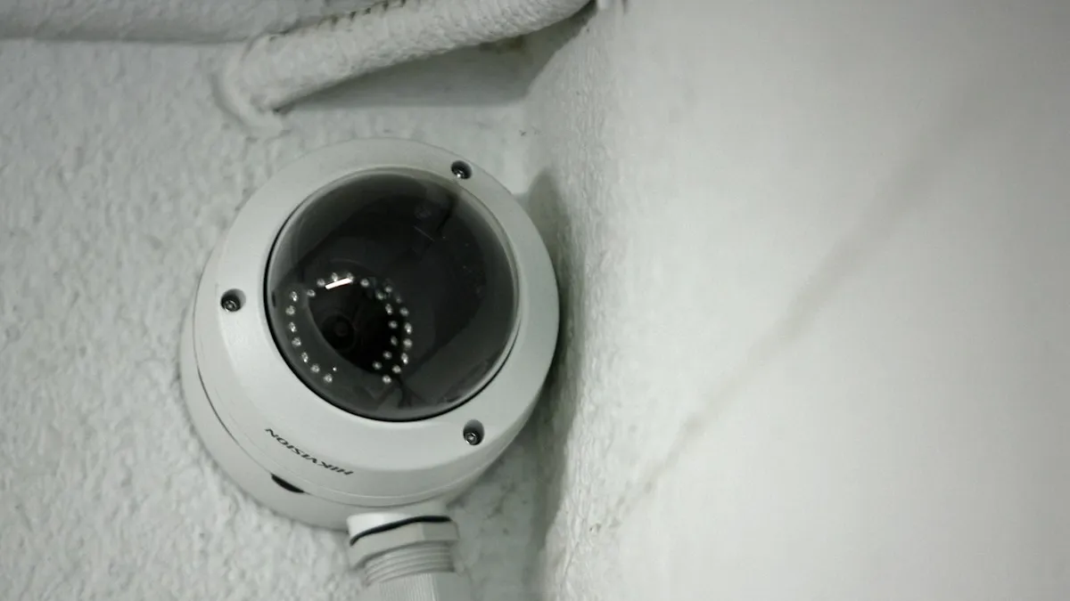 Câmera dome branca fixada no canto de uma parede de reboco, exemplo de instalação no alto
