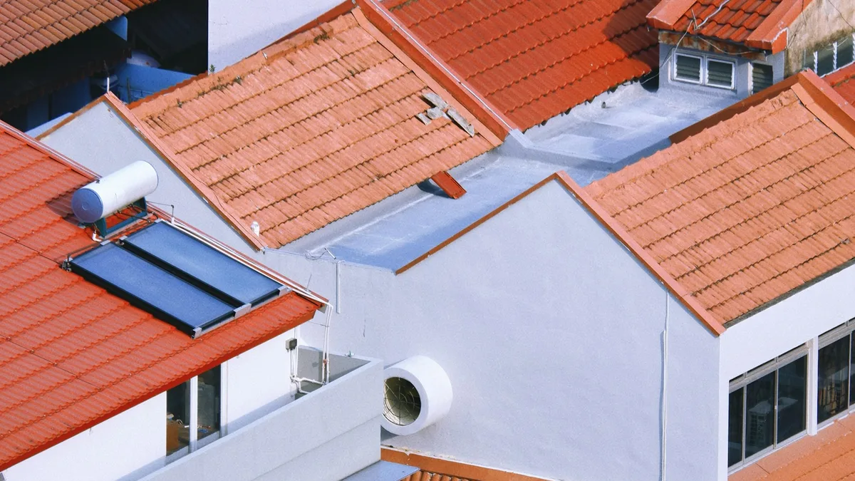 Telhados de casas vistos de cima, com placas solares e telhas alaranjadas