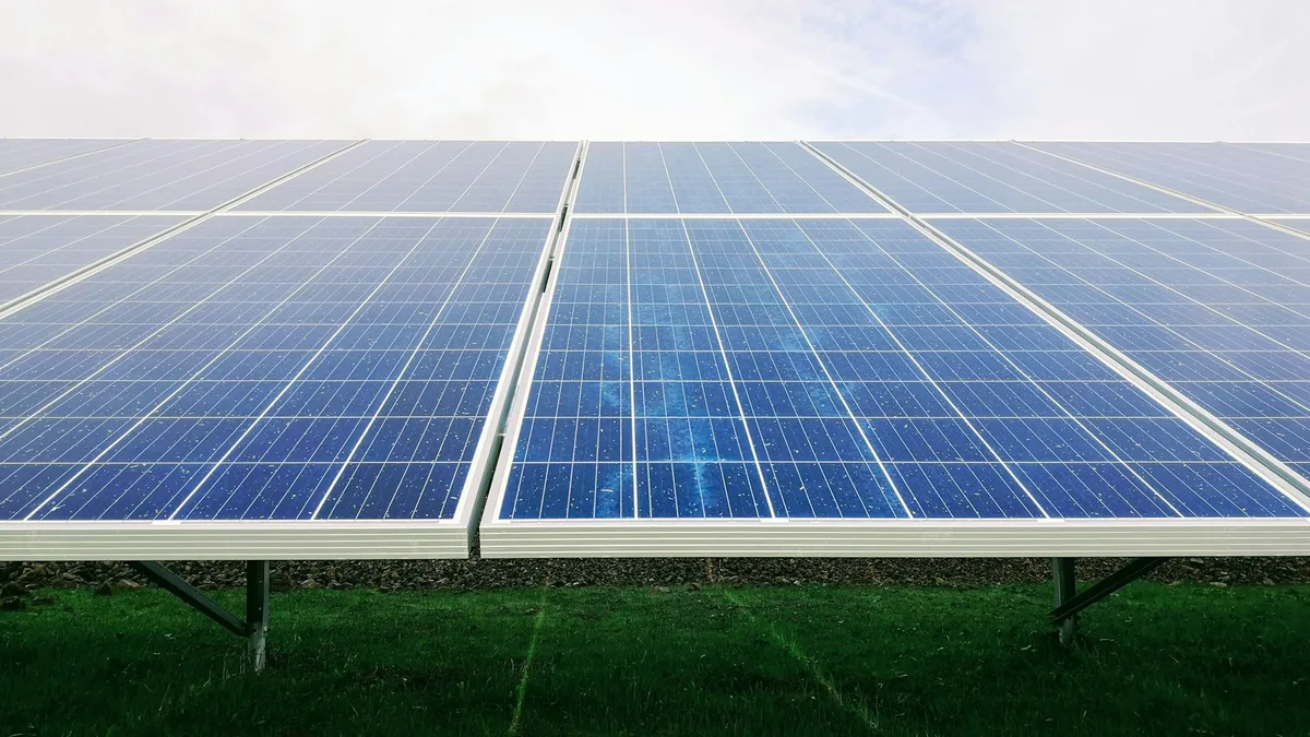 Painel solar fotovoltaico em primeiro plano sobre gramado e céu claro