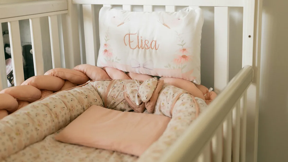 Berço branco com roupa de cama rosa em um quarto de bebê claro