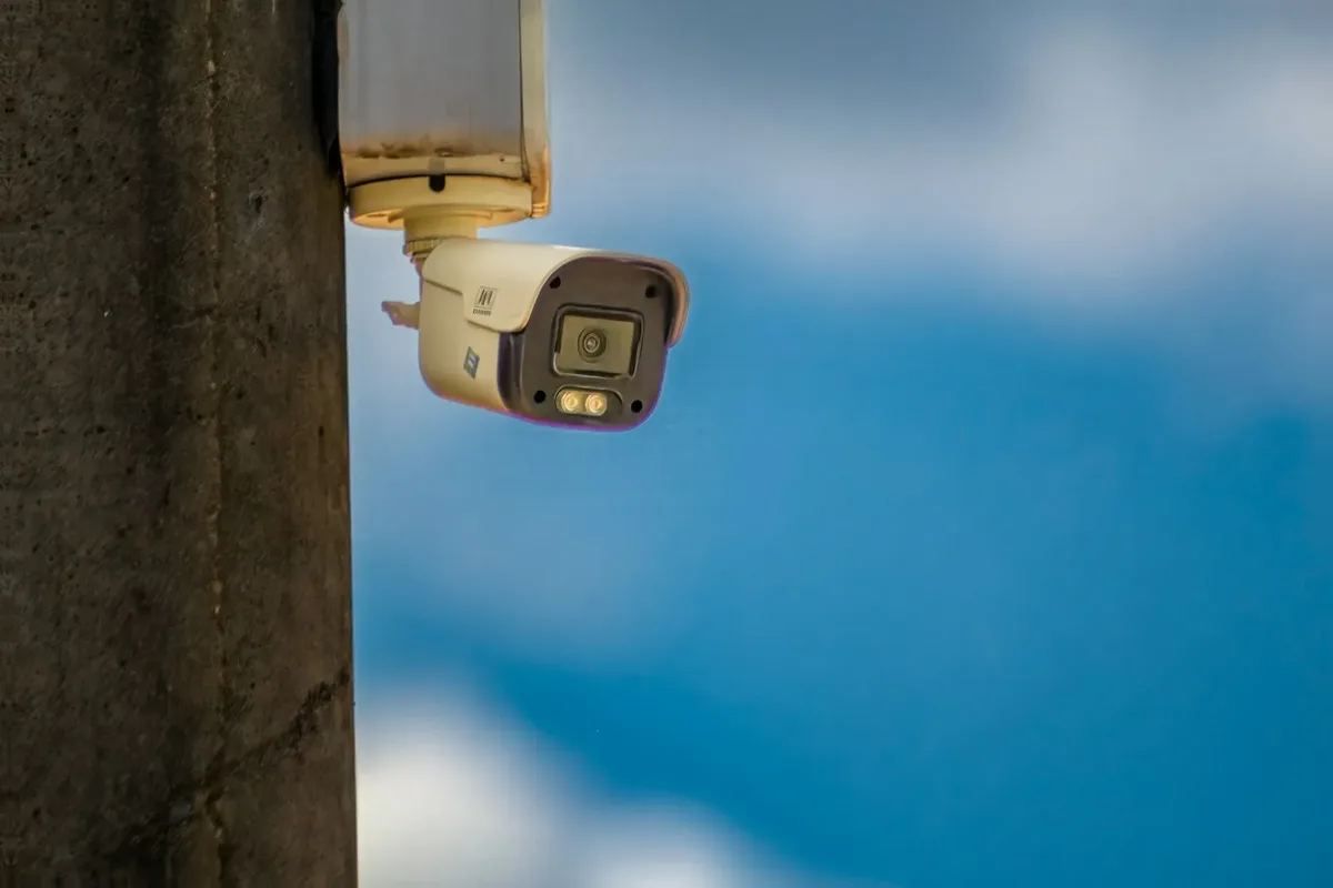 Câmera de segurança para ambientes externos instalada em poste contra o céu azul