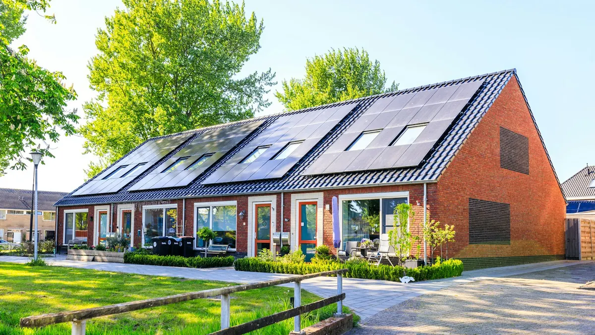Casa de tijolos com painéis solares no telhado e gramado em frente, cenário típico para uma câmera de segurança sem fio solar