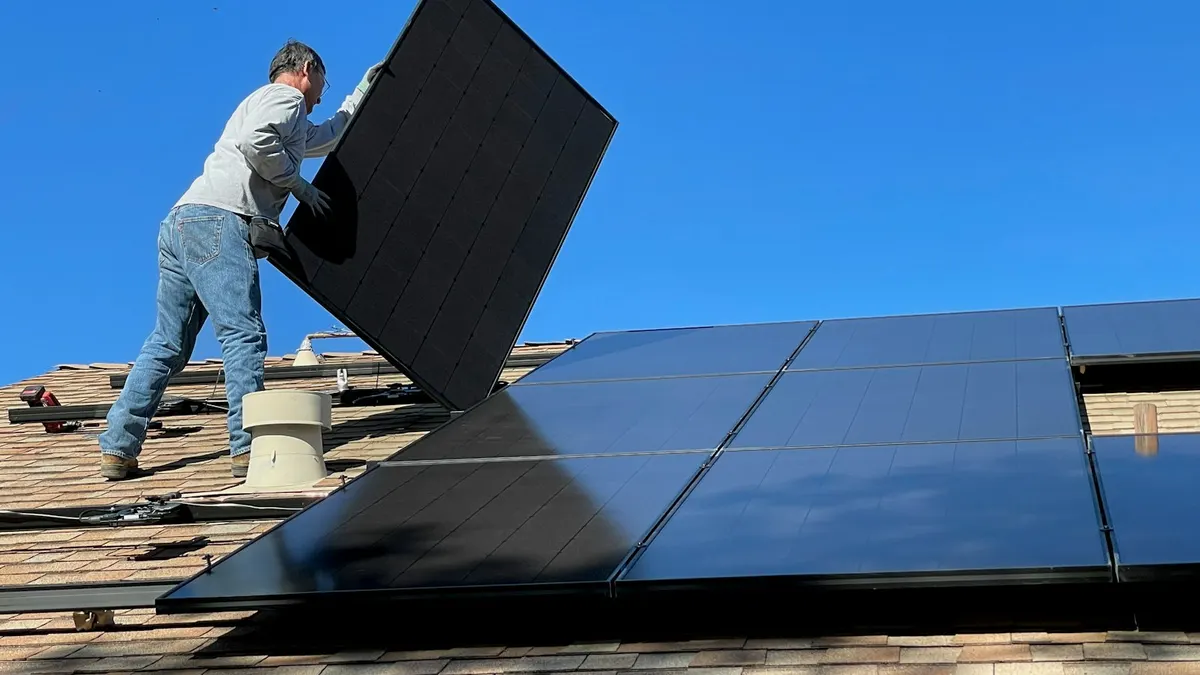 Instalador carregando um painel solar sobre um telhado, imagem que lembra o posicionamento do painel de uma câmera de segurança sem fio solar