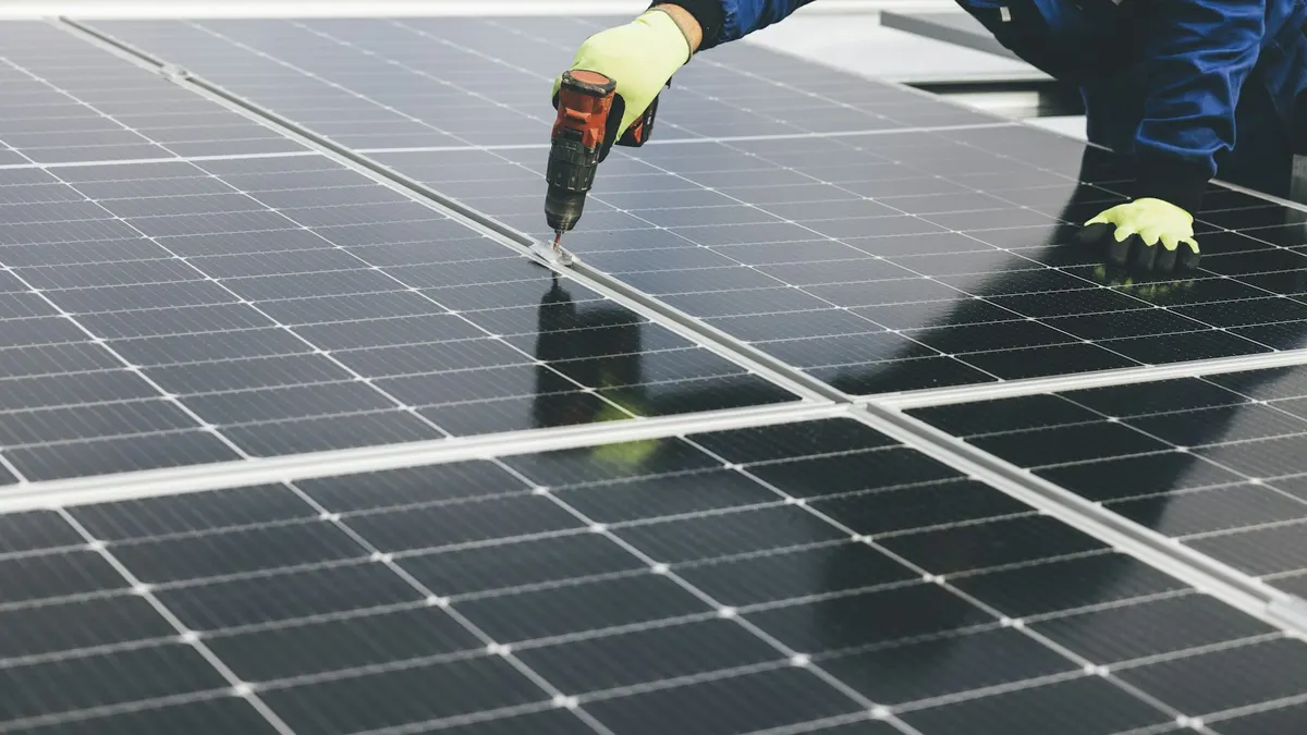Mão com furadeira fixando um painel solar, ilustrando a instalação de uma câmera de segurança sem fio solar