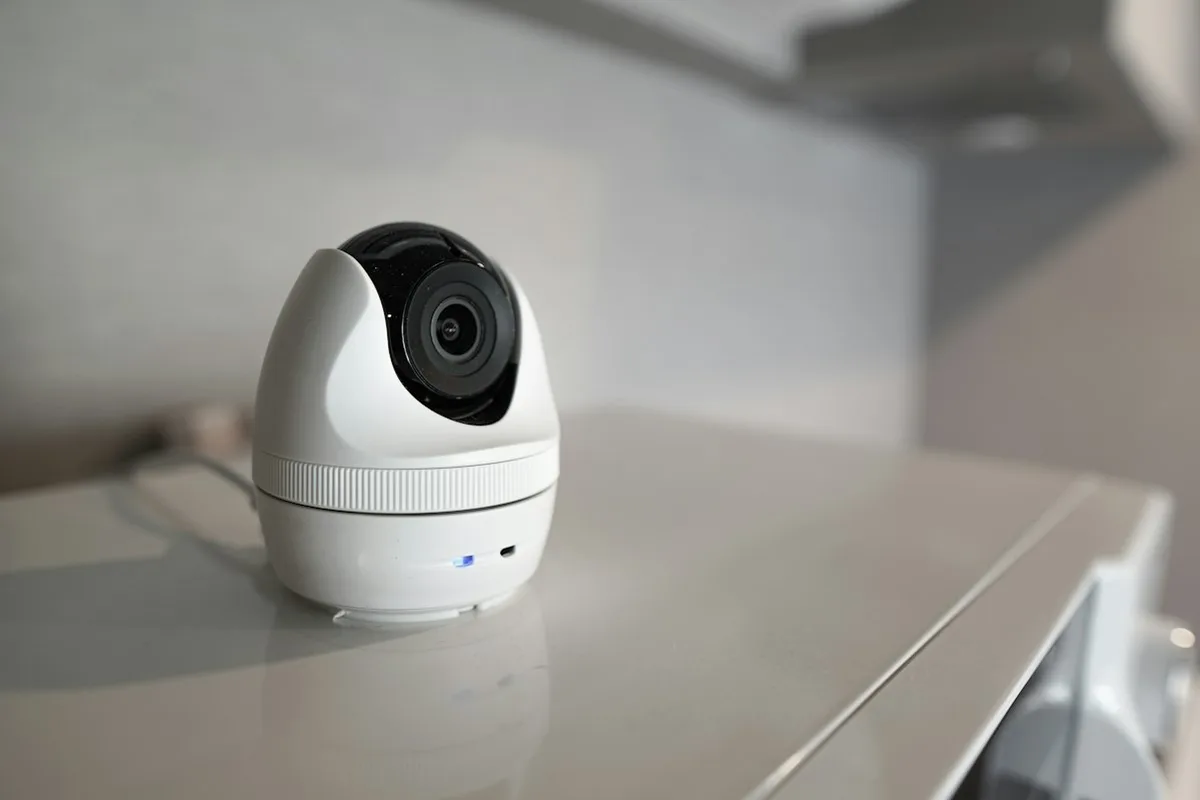 Câmera de segurança wifi branca em formato de cúpula sobre uma estante
