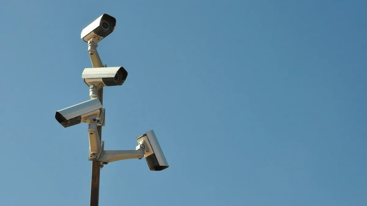 Quatro câmeras de segurança em um poste contra o céu azul, exemplo de câmera Intelbras externa em área aberta