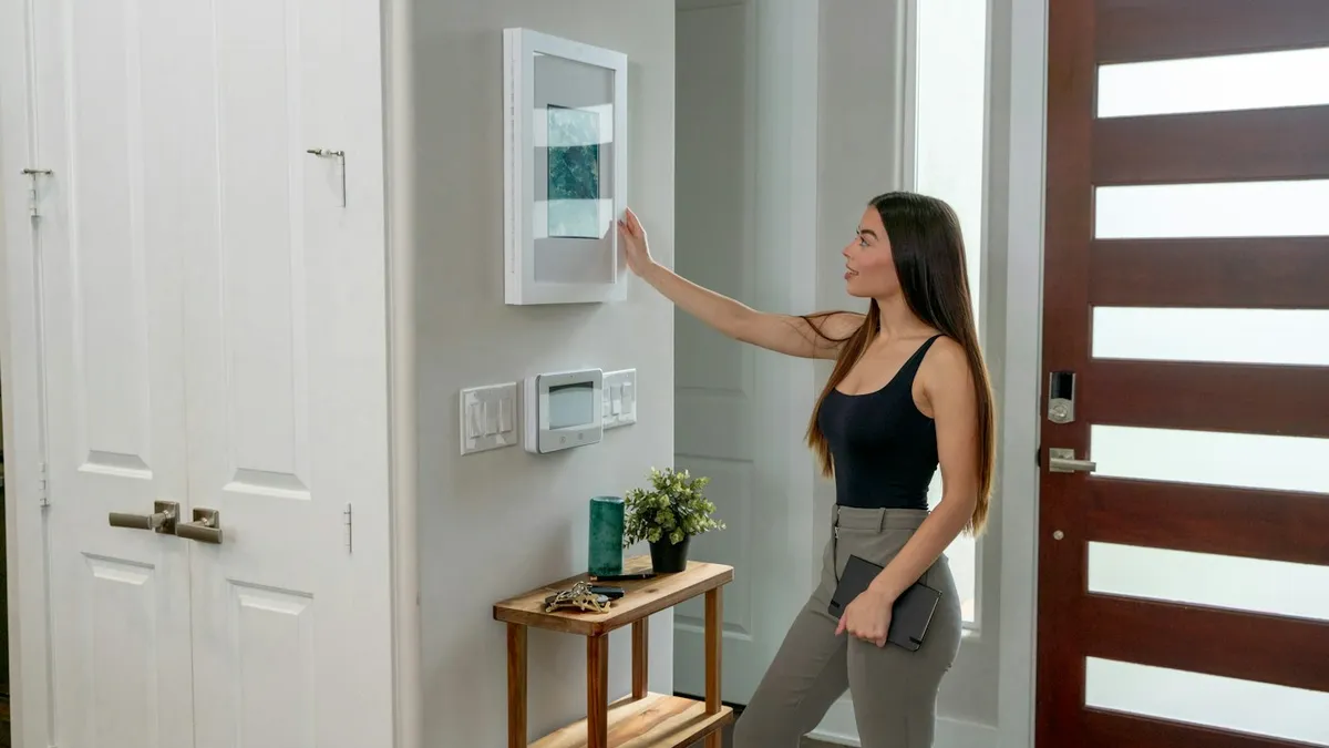 Mulher usando um painel de controle de casa inteligente instalado na parede da entrada
