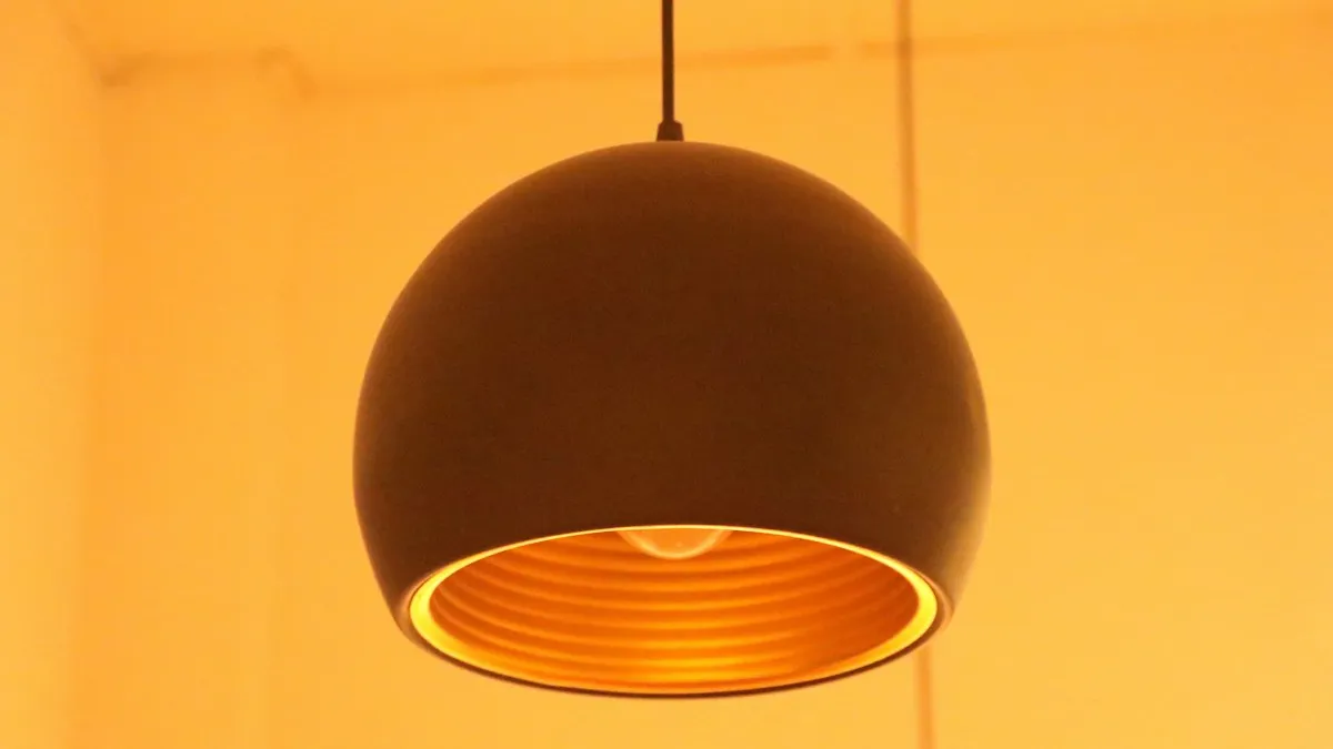 Luminária pendente laranja acesa em um teto, ambiente em que uma câmera Jortan em formato de lâmpada pode ser instalada