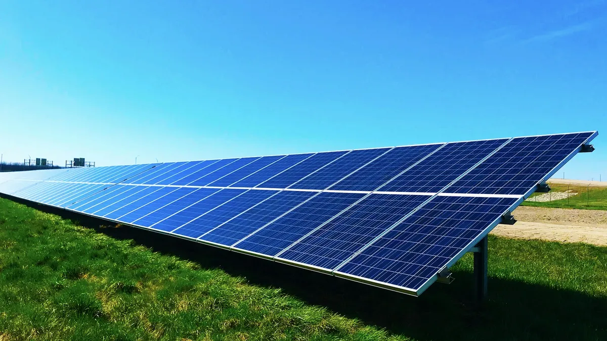Painel solar inclinado sobre um gramado com céu azul, o mesmo princípio que alimenta uma câmera solar