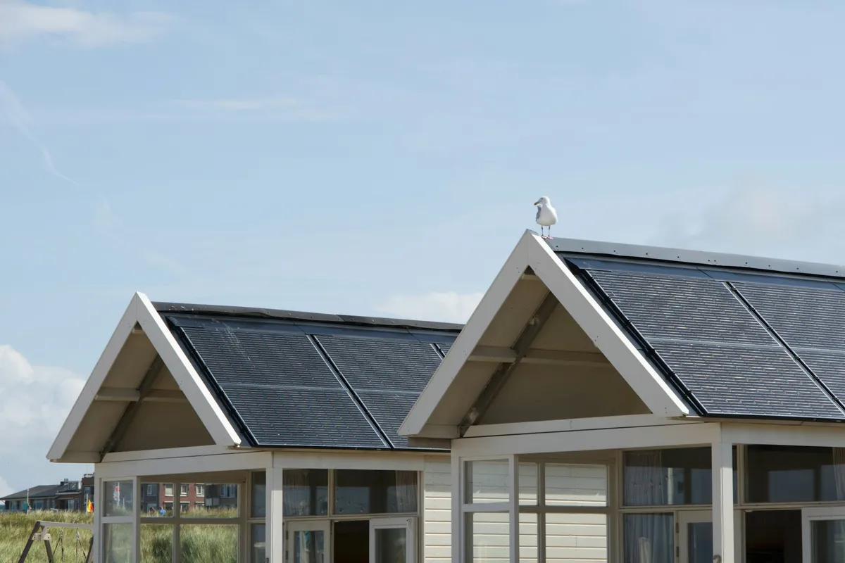 Casas com painéis solares no telhado sob céu azul, cenário típico de uma câmera solar