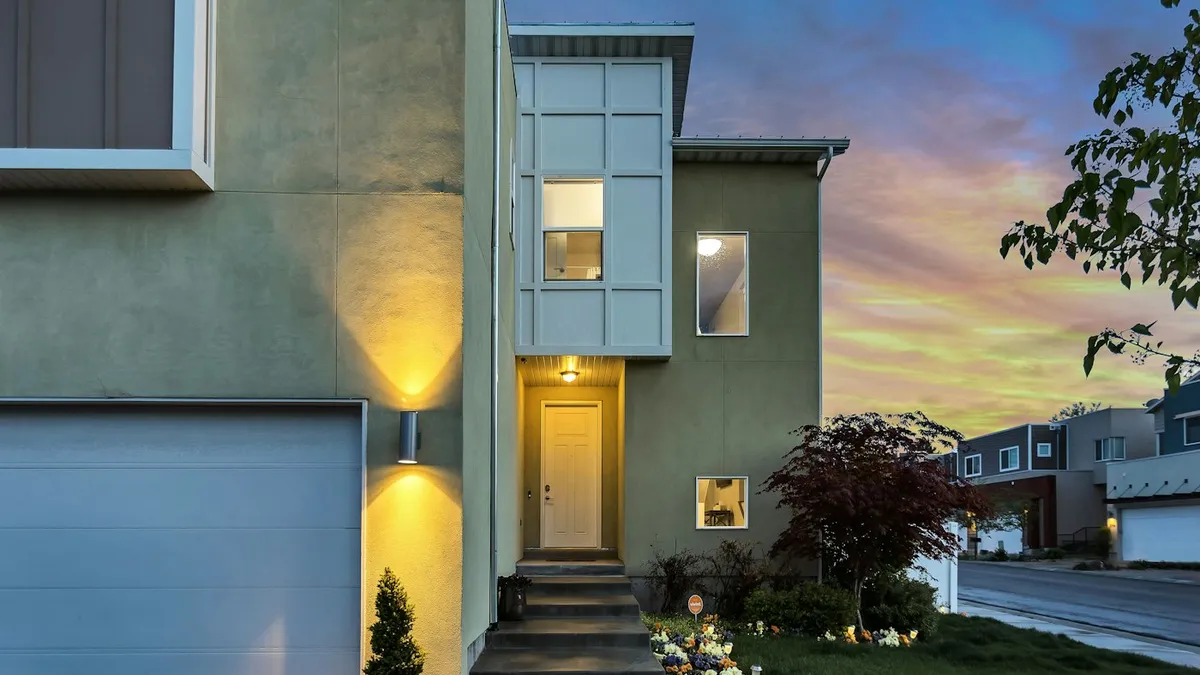 Fachada de casa com porta azul e lanternas acesas ao entardecer, ponto comum para uma câmera Xiaomi externa