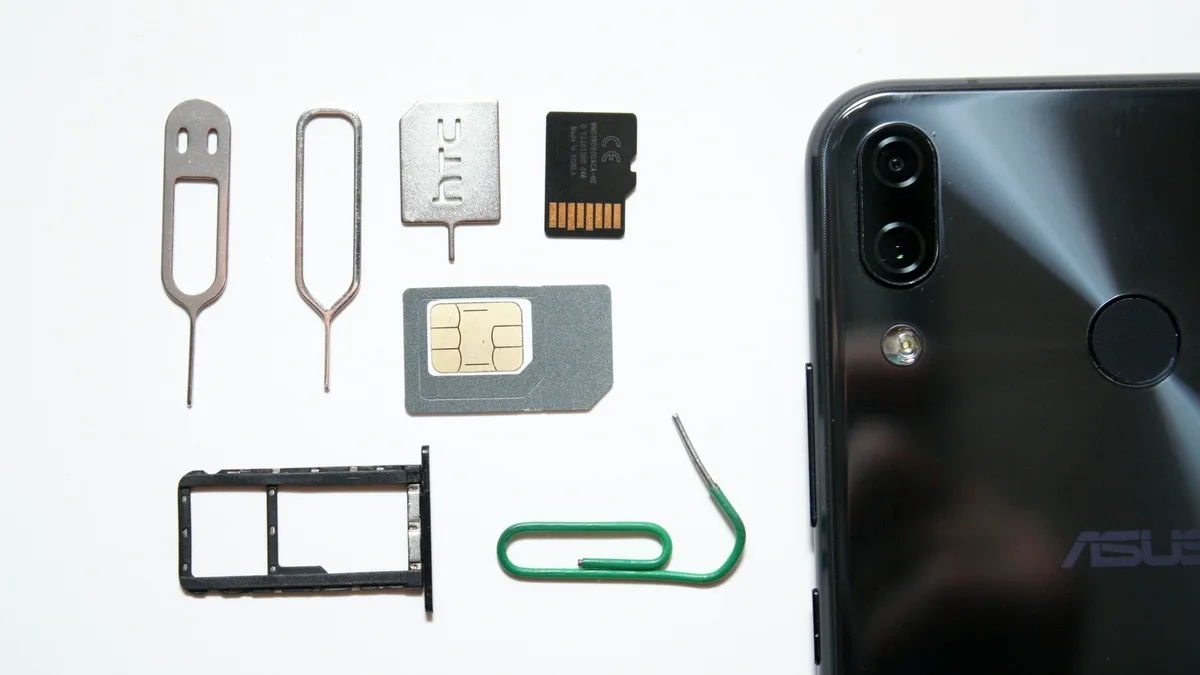 Cartão de memória microSD ao lado de um notebook sobre uma mesa de madeira