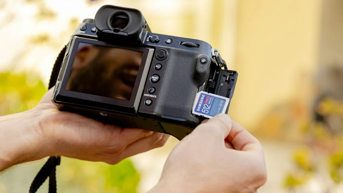 Mão inserindo um cartão de memória microSD no encaixe de uma câmera