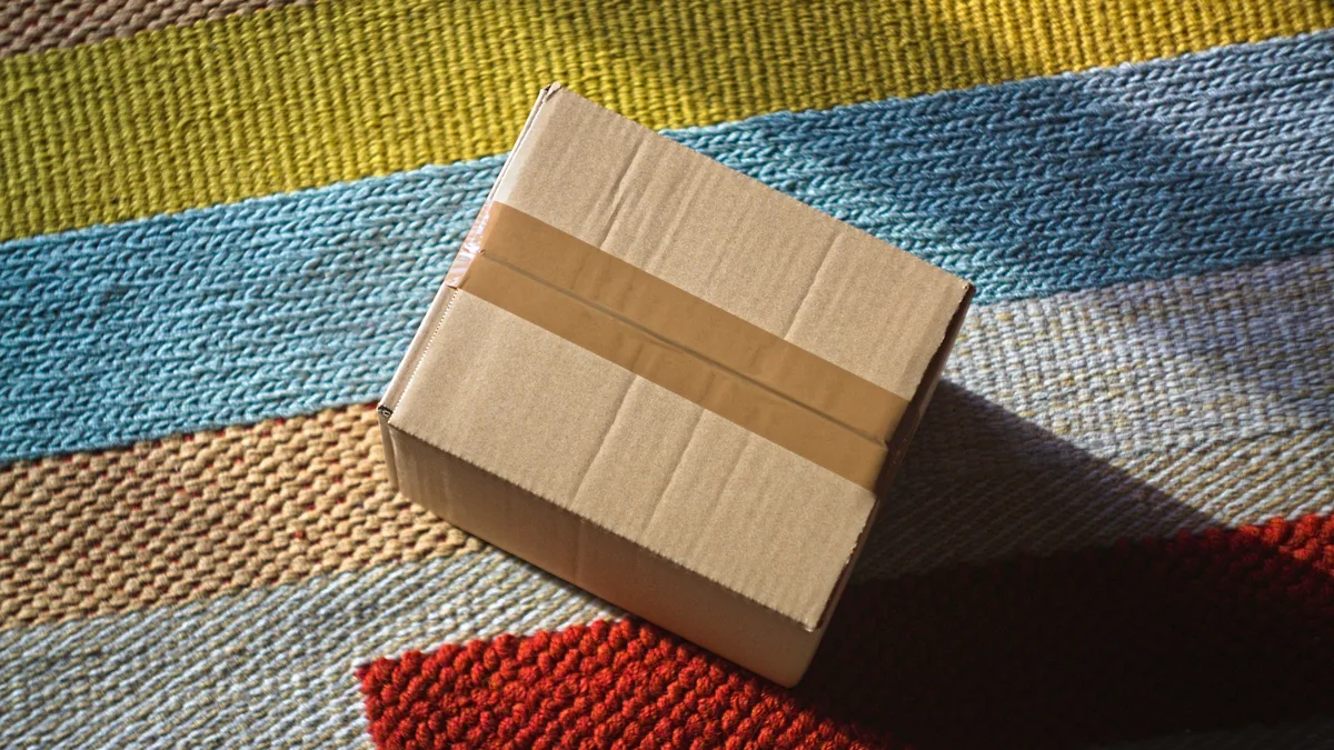Caixa de papelão fechada sobre um tapete colorido, representando a câmera recém-comprada