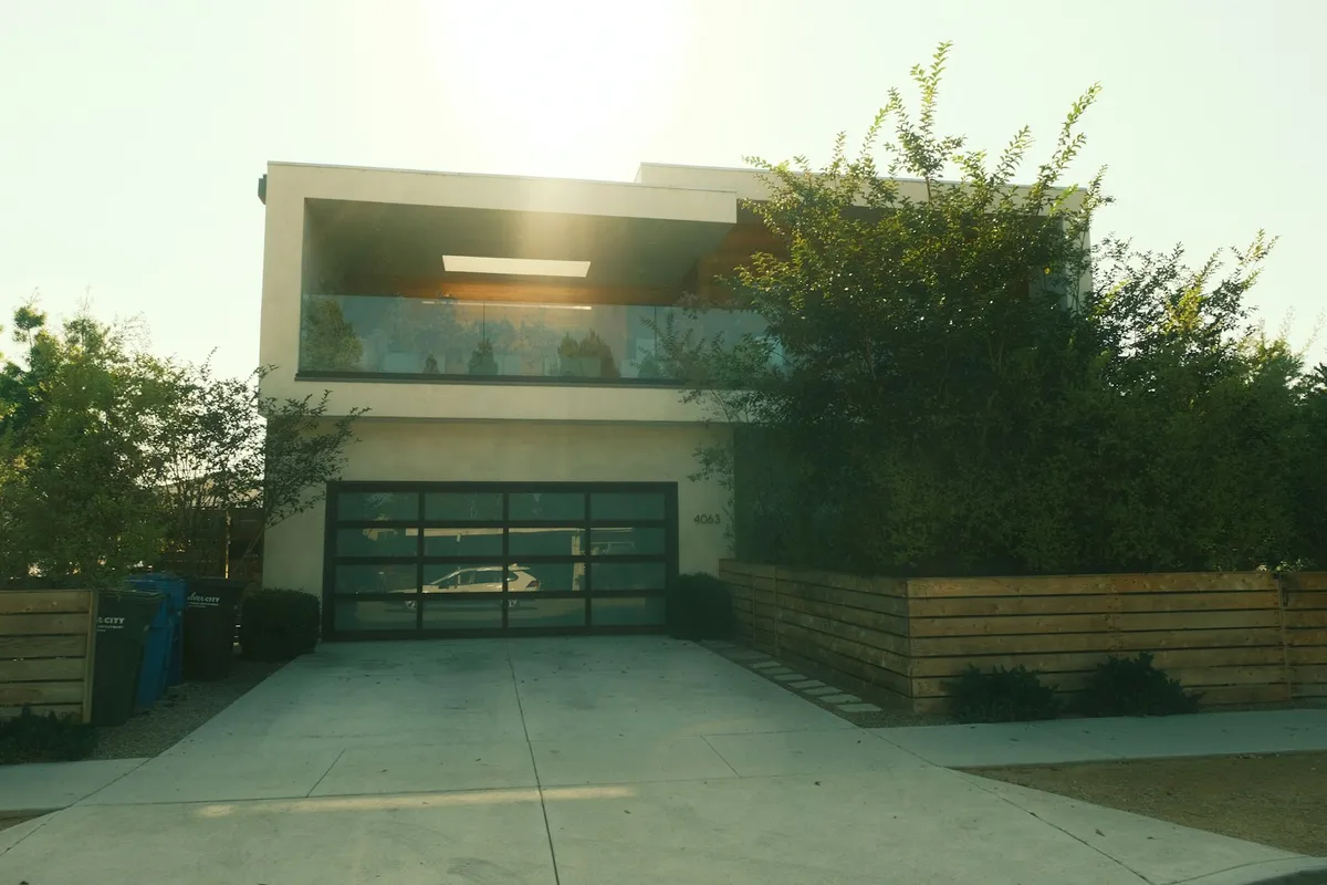 Casa moderna de dois andares com garagem, jardim e calçada ao entardecer
