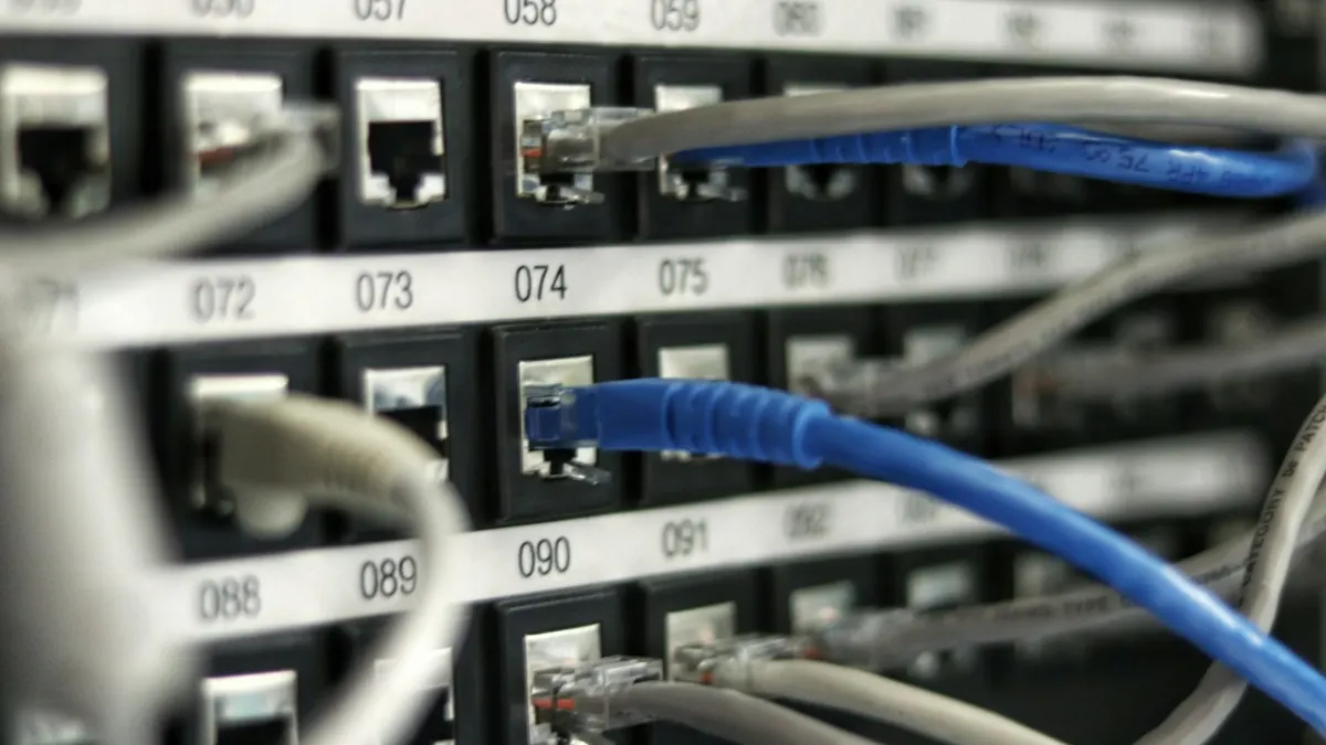 Cabos de rede azuis e cinza conectados a um painel de patch com portas numeradas