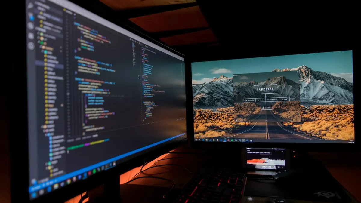 Mesa com monitor e notebook exibindo imagens de câmeras de segurança