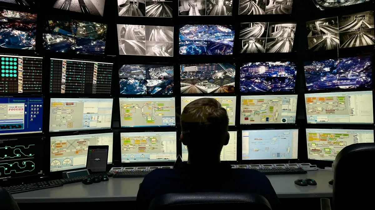 Homem observando parede com vários monitores de câmeras