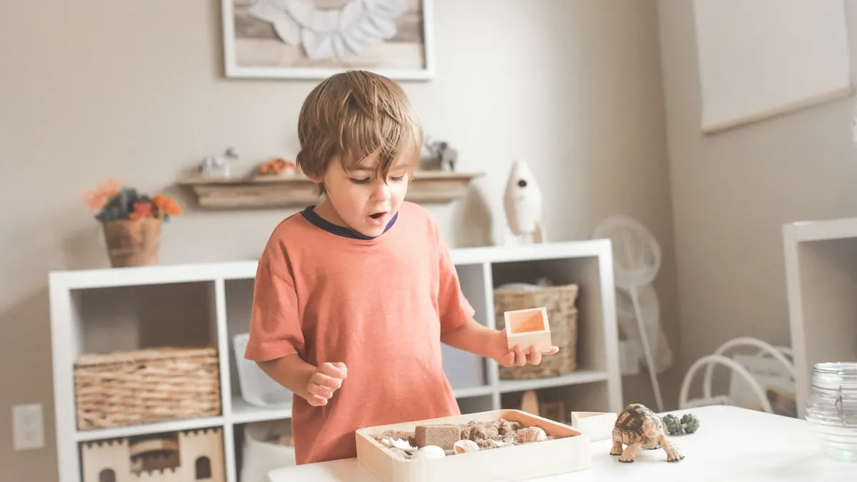 Criança brincando ao lado de uma estante com brinquedos, cena doméstica comum em cômodos monitorados
