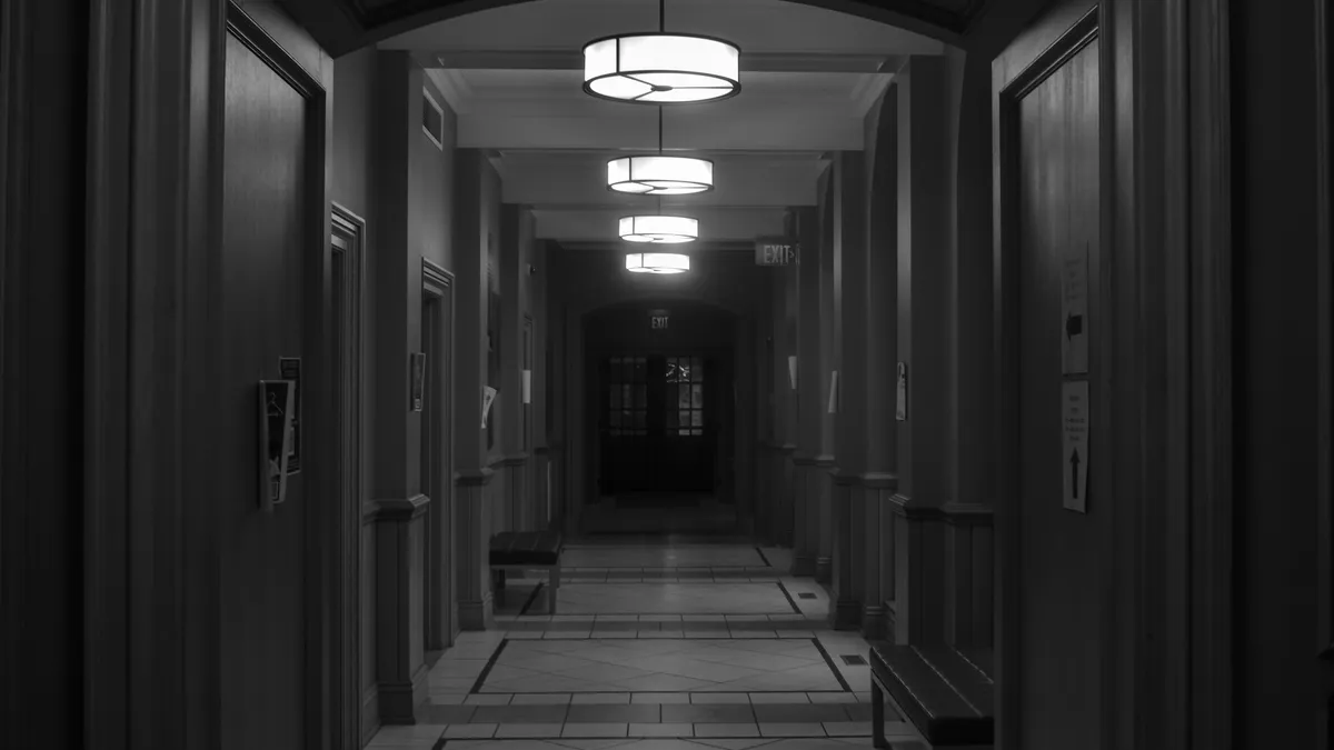 Corredor escuro de uma casa com luzes de teto acesas, local típico para um sensor de presença do kit alarme residencial