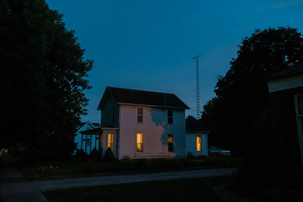 Casa ao anoitecer com luzes acesas nas janelas, ambiente protegido por um kit alarme residencial