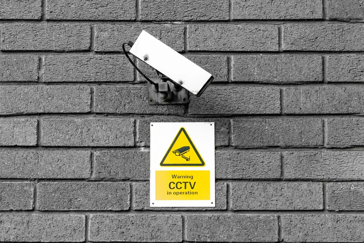 Câmera de segurança falsa e placa de aviso CCTV em parede de tijolos