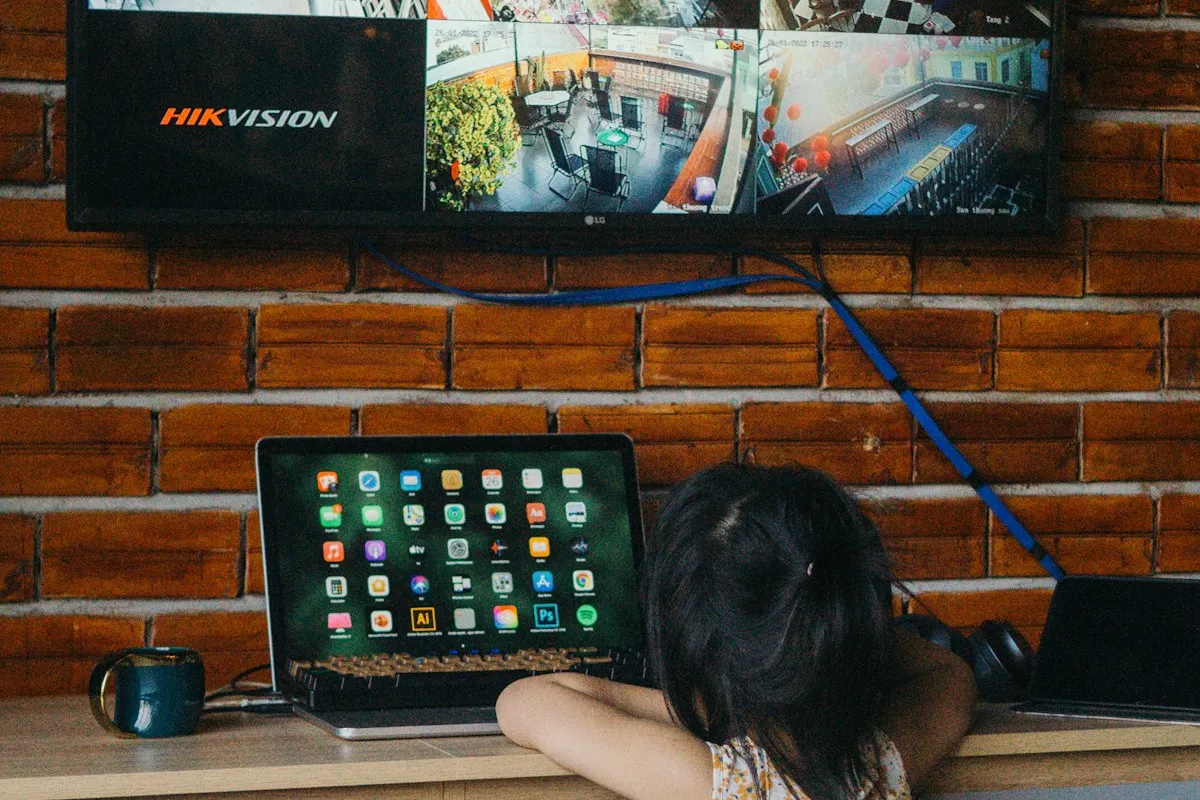 Crianças diante de um monitor Hikvision que exibe várias câmeras de um sistema de segurança