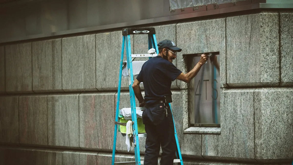 Técnico instalando câmera de segurança em parede com escada