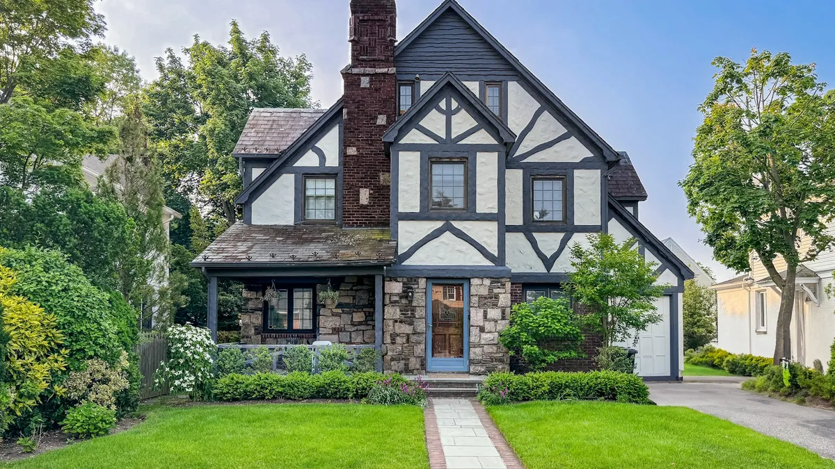 Casa de dois andares com jardim na frente, exemplo de imóvel que recebe um alarme para casa
