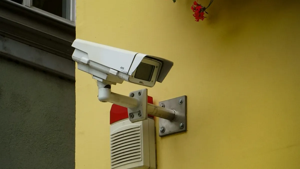Câmera de segurança branca instalada em parede amarela