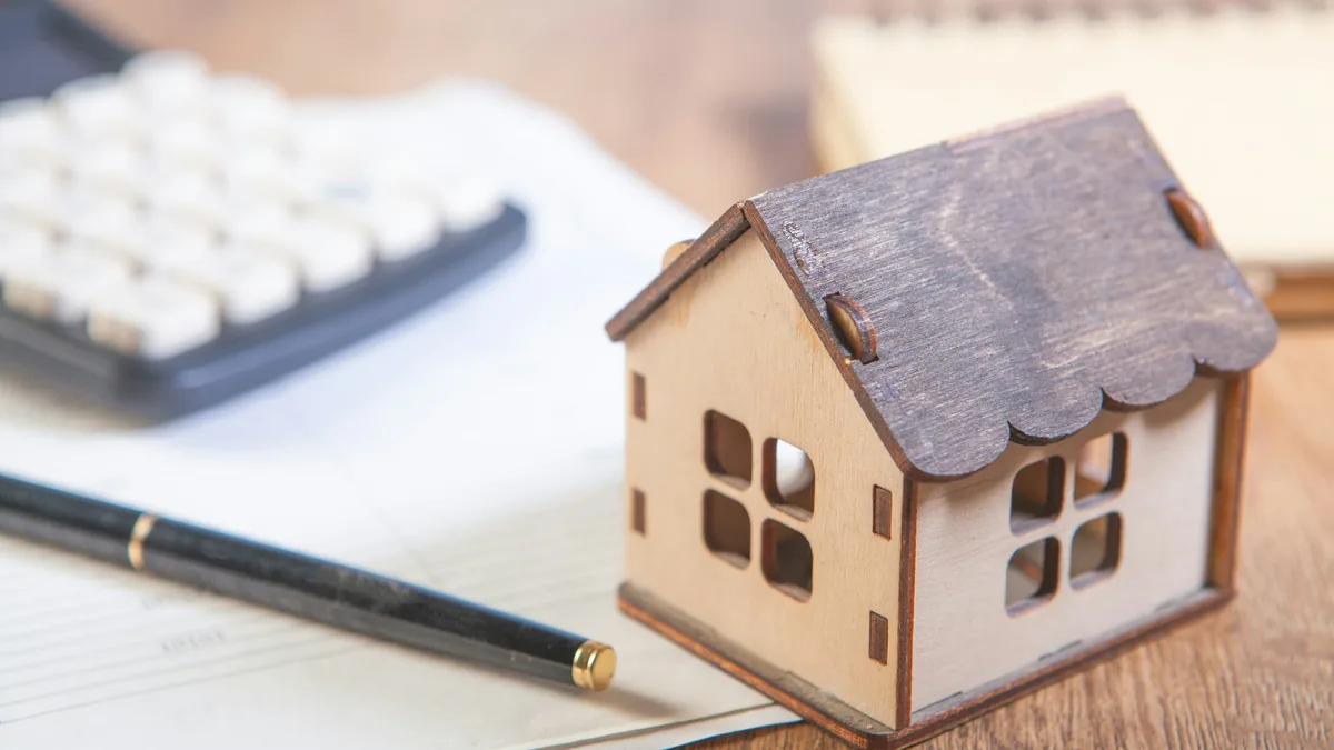 Casa em miniatura ao lado de calculadora e caneta, simbolizando o orçamento da segurança