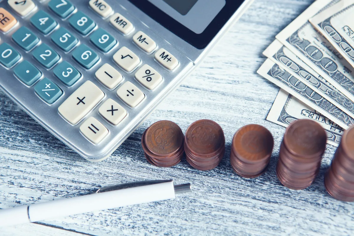Calculadora, moedas e notas sobre a mesa para calcular quanto custa câmera de segurança