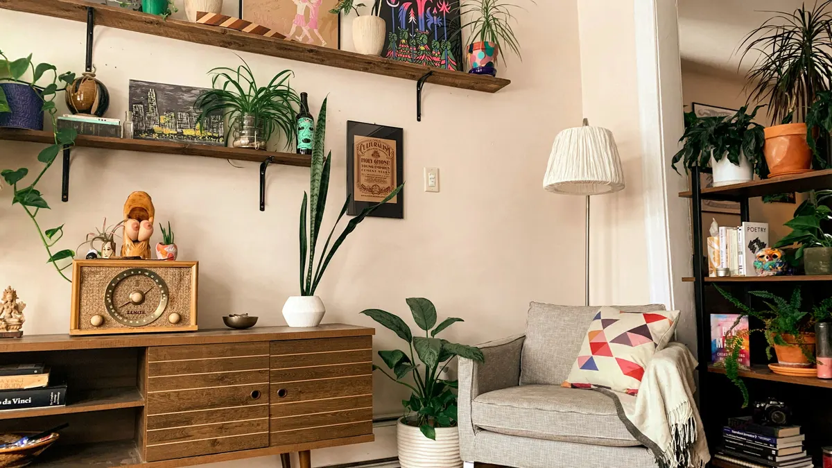 Estante de madeira com plantas e objetos decorativos sobre um aparador, ponto típico para apoiar uma câmera pequena