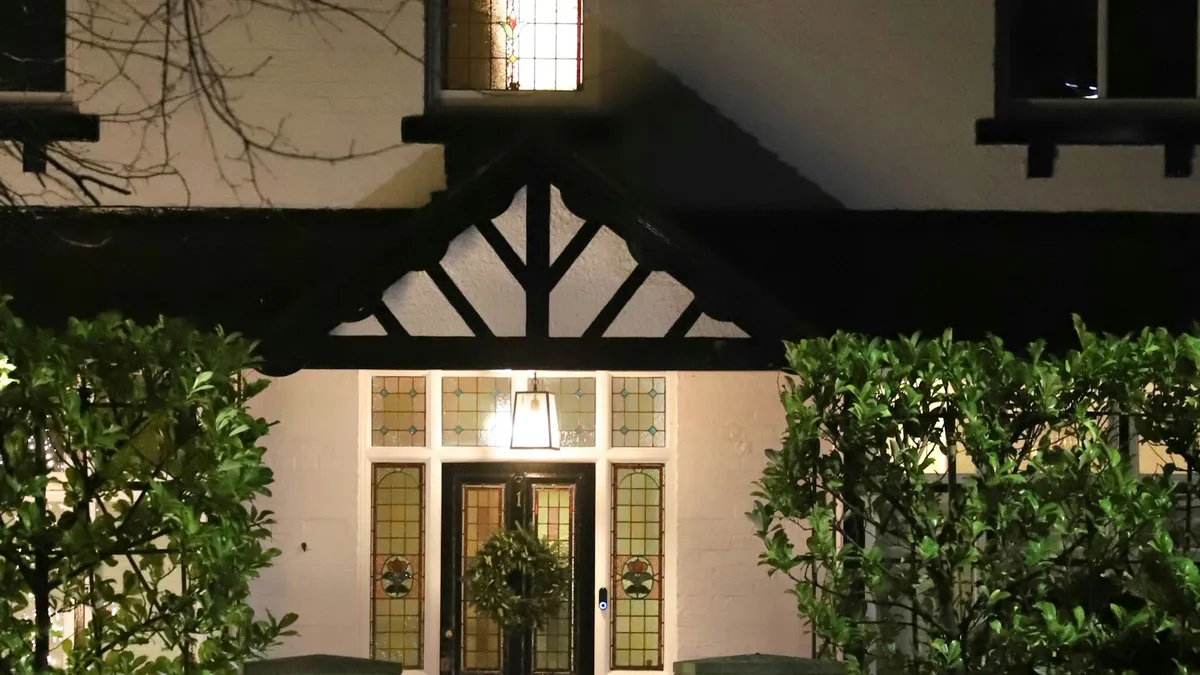 Fachada de uma casa à noite com luz acesa na entrada, ponto típico para instalar uma câmera externa