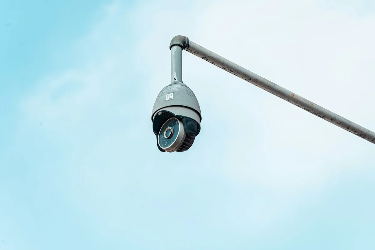 Câmera de segurança em cúpula giratória em braço de parede contra o céu claro