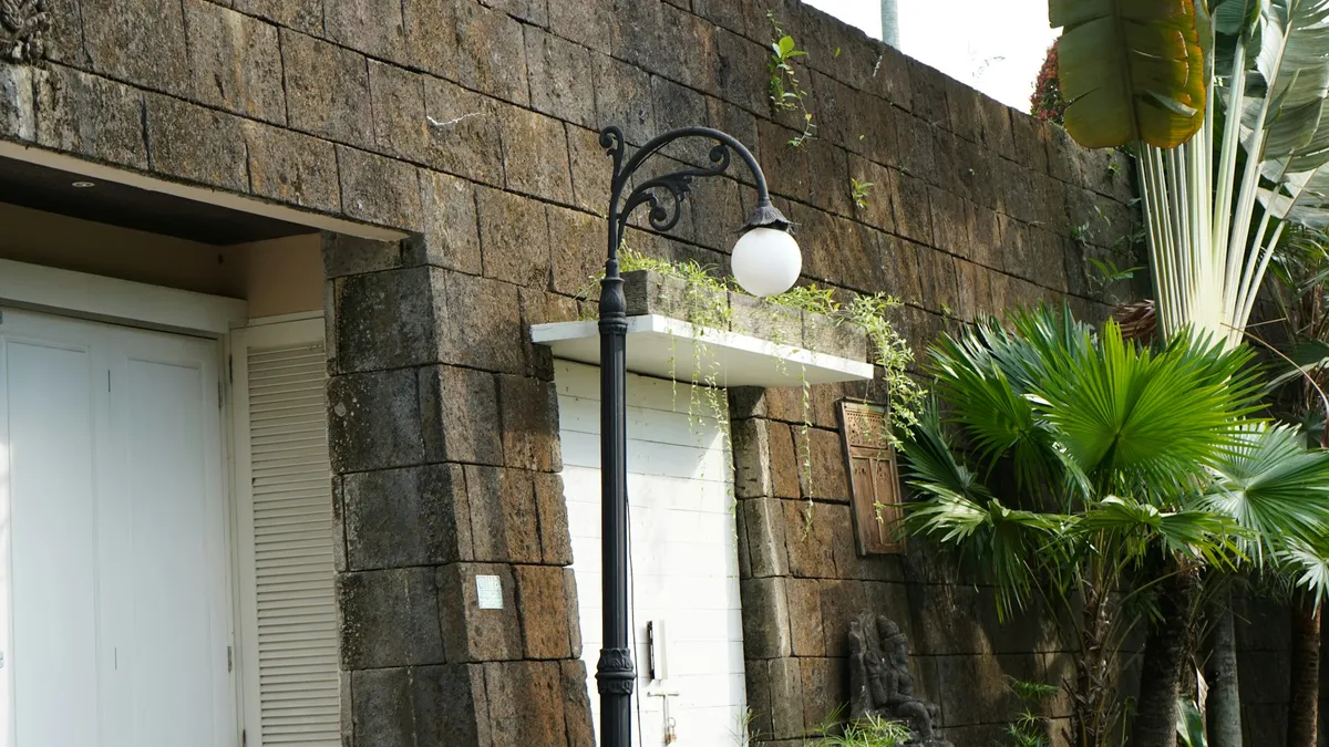 Entrada de casa com muro de pedra e poste de luz, local típico para instalar um vídeo porteiro