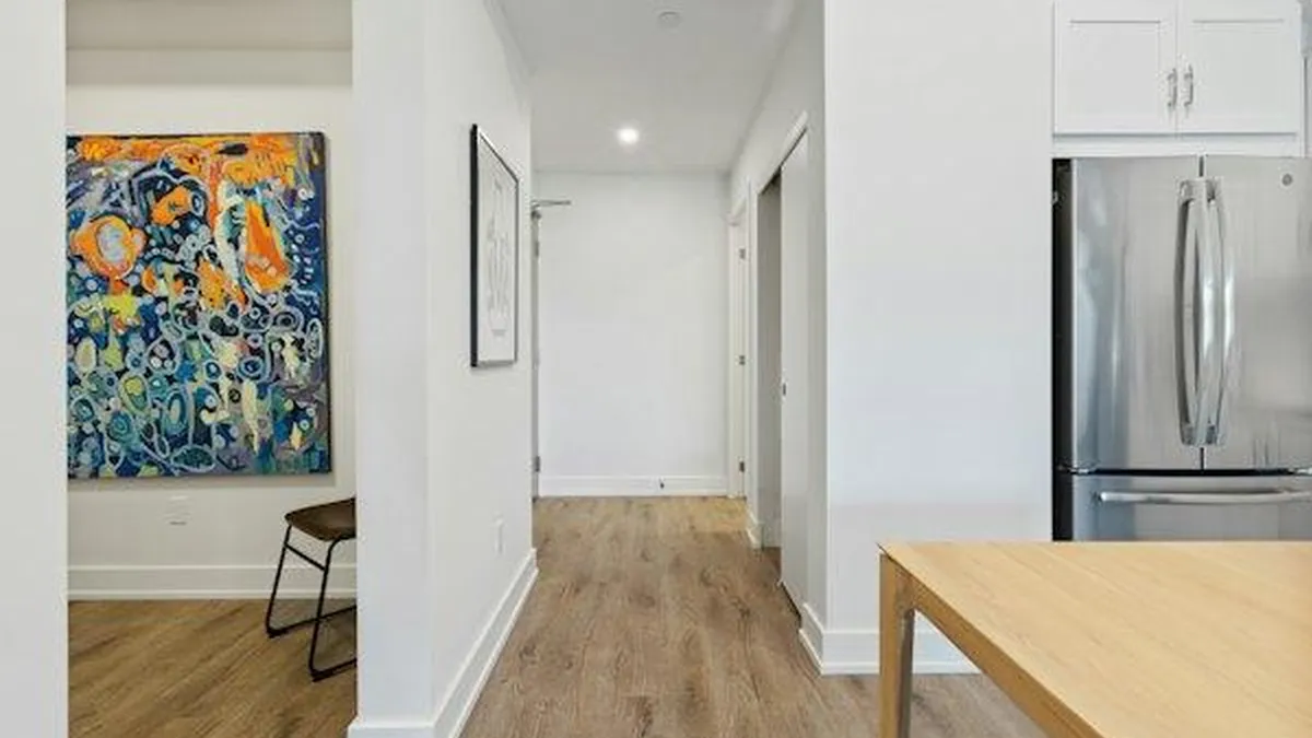 Corredor de apartamento com piso de madeira clara e paredes brancas, ponto comum de instalação de câmera interna